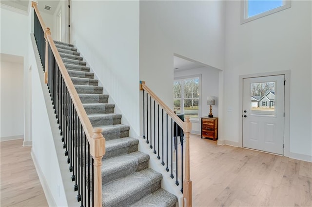 foyer with a wealth of natural light, a towering ceiling, and light wood finished floors