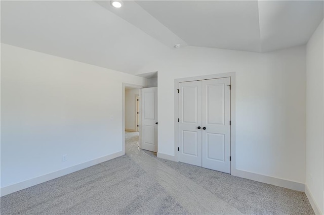 unfurnished bedroom with vaulted ceiling, carpet flooring, baseboards, and a closet