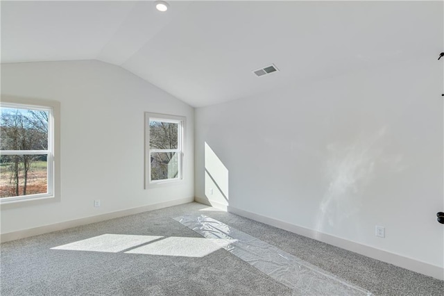 carpeted spare room with visible vents, baseboards, and vaulted ceiling