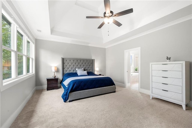 carpeted bedroom featuring baseboards, ornamental molding, ceiling fan, ensuite bathroom, and a raised ceiling