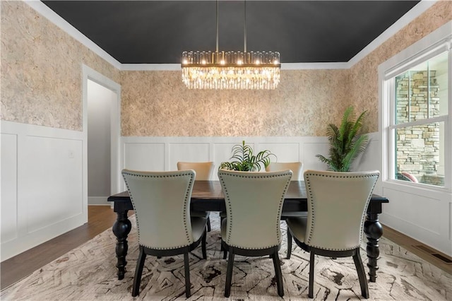 dining space with a notable chandelier, crown molding, and wood-type flooring