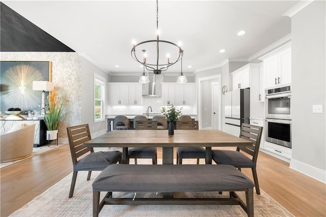 dining area with sink, ornamental molding, light hardwood / wood-style floors, and a chandelier