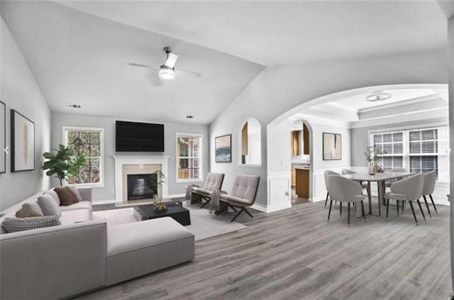 living room with ceiling fan, wood-type flooring, and vaulted ceiling