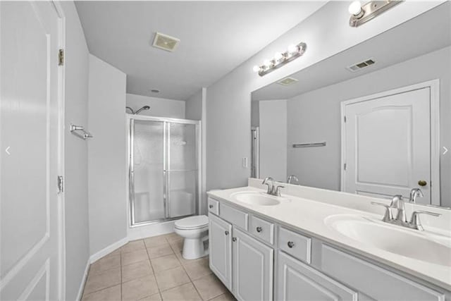 bathroom with tile patterned flooring, vanity, a shower with shower door, and toilet