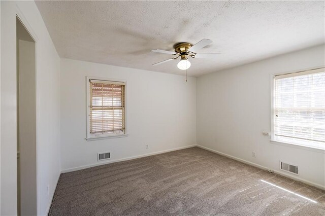 spare room featuring ceiling fan, a textured ceiling, and dark carpet