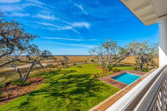 view of pool with a rural view and a lawn