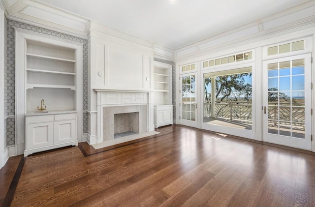 unfurnished living room with a premium fireplace, built in features, and dark wood-type flooring