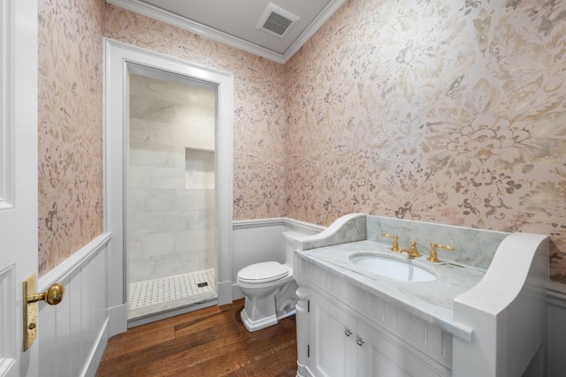 bathroom featuring crown molding, hardwood / wood-style floors, toilet, tiled shower, and vanity