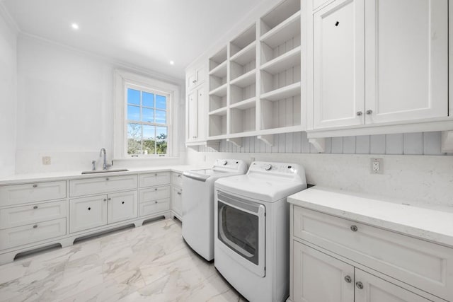 laundry area with cabinets, washing machine and dryer, crown molding, and sink