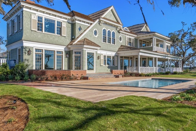 back of house with a lawn, a balcony, and a patio