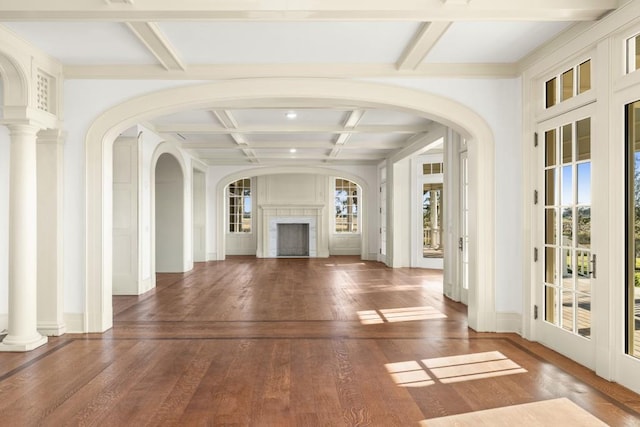 unfurnished living room featuring beamed ceiling, a healthy amount of sunlight, dark wood-type flooring, and coffered ceiling