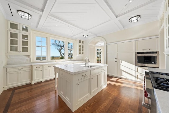 kitchen featuring dark hardwood / wood-style flooring, a center island with sink, oven, and sink