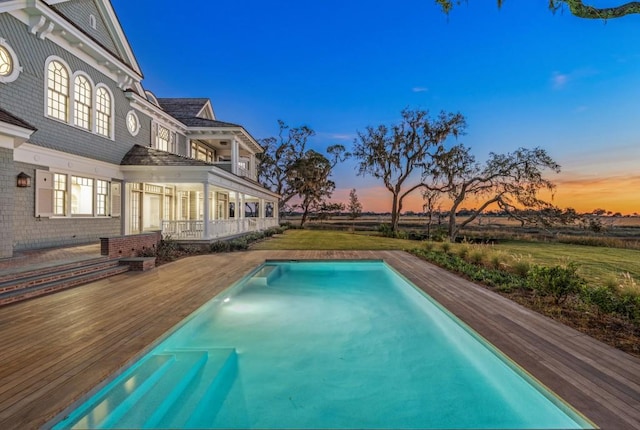 pool at dusk featuring a deck