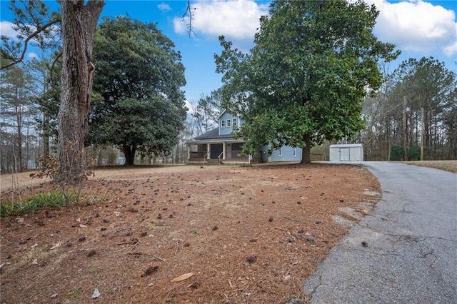 view of front of home with a garage, covered porch, aphalt driveway, and an outbuilding