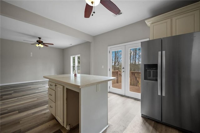 kitchen with cream cabinets, light countertops, french doors, a center island, and stainless steel fridge