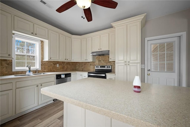 kitchen featuring light countertops, visible vents, appliances with stainless steel finishes, a sink, and under cabinet range hood