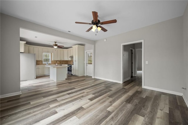 unfurnished living room featuring ceiling fan, baseboards, and wood finished floors