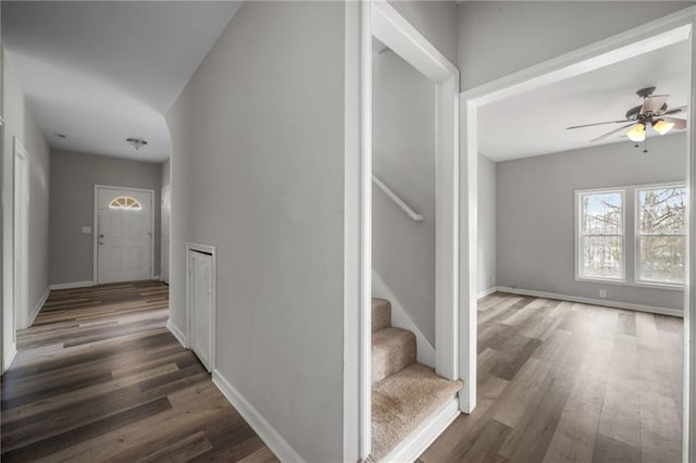 interior space featuring dark wood-style floors, baseboards, stairway, and ceiling fan