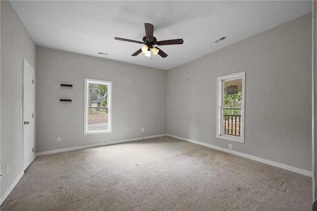 empty room featuring baseboards, visible vents, and light colored carpet