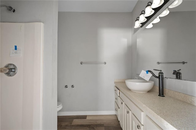 bathroom with baseboards, vanity, toilet, and wood finished floors