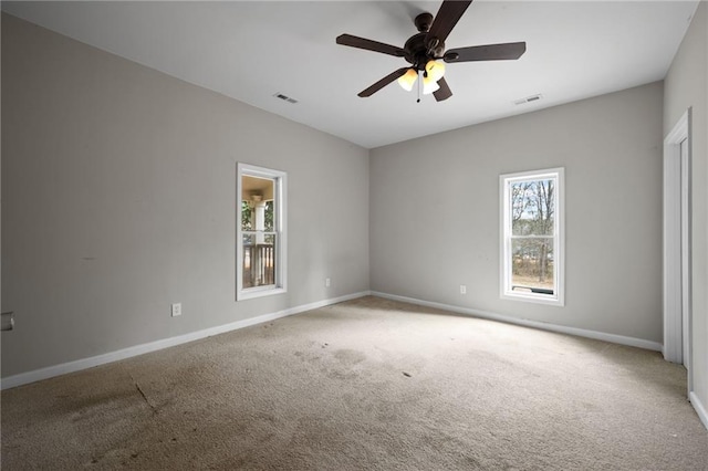 spare room featuring carpet floors, a ceiling fan, visible vents, and baseboards