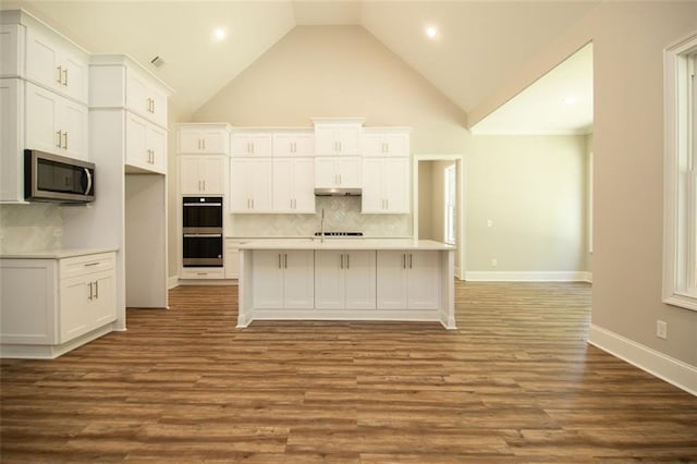 kitchen with decorative backsplash, white cabinets, and multiple ovens