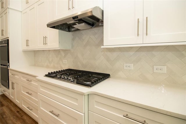 kitchen with stainless steel gas stovetop, dark wood-type flooring, white cabinets, black double oven, and decorative backsplash