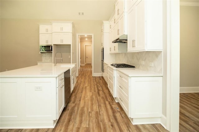 kitchen featuring appliances with stainless steel finishes, tasteful backsplash, sink, white cabinetry, and an island with sink