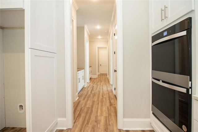 interior space with white cabinets, stainless steel double oven, light hardwood / wood-style floors, and ornamental molding