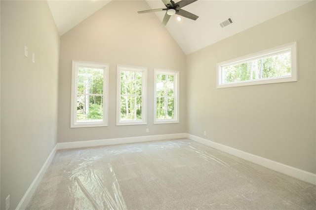 empty room featuring ceiling fan, high vaulted ceiling, a healthy amount of sunlight, and light carpet