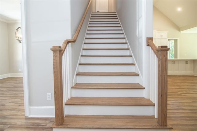 staircase featuring wood-type flooring and ornamental molding