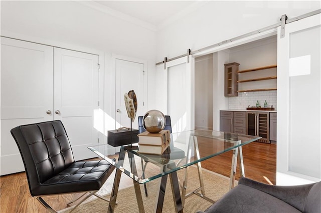 interior space featuring hardwood / wood-style flooring, beverage cooler, a barn door, and crown molding