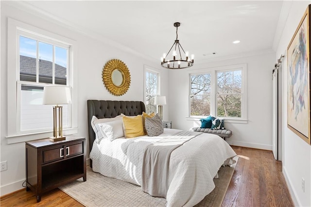 bedroom with crown molding, wood-type flooring, an inviting chandelier, and multiple windows