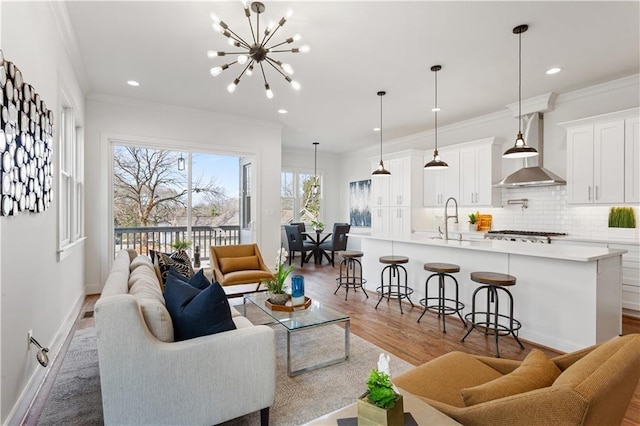 living room featuring hardwood / wood-style flooring, ornamental molding, sink, and a notable chandelier