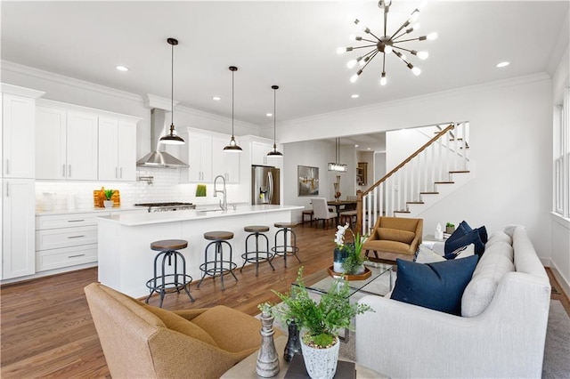 living room featuring dark hardwood / wood-style flooring, sink, a notable chandelier, and ornamental molding