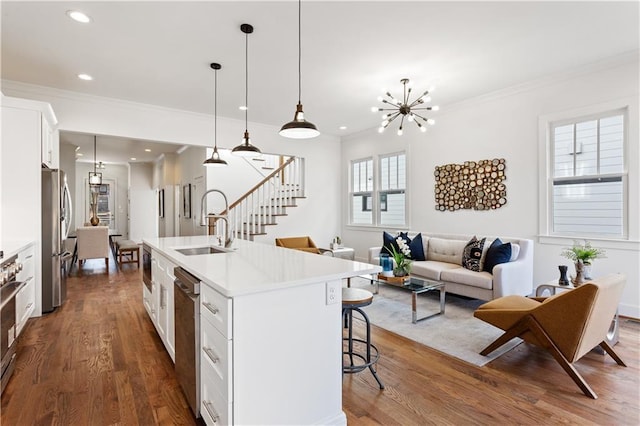 kitchen featuring a breakfast bar, white cabinetry, decorative light fixtures, an island with sink, and stainless steel appliances