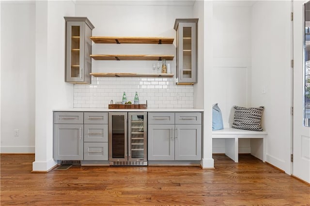 bar with wine cooler, dark hardwood / wood-style floors, tasteful backsplash, and gray cabinetry