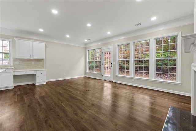 unfurnished living room featuring built in desk, crown molding, plenty of natural light, and dark wood-type flooring