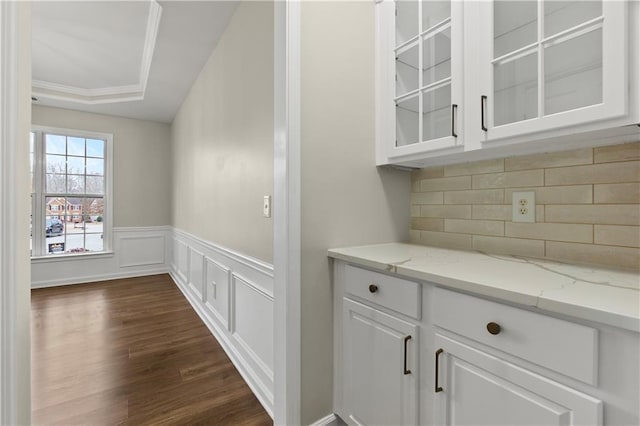 bar with light stone countertops, backsplash, a raised ceiling, dark hardwood / wood-style floors, and white cabinetry