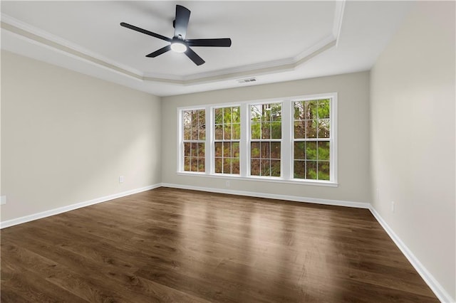 spare room featuring dark hardwood / wood-style floors, ceiling fan, ornamental molding, and a tray ceiling