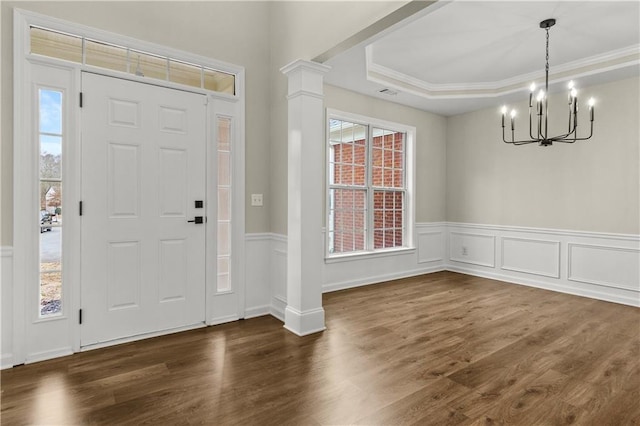 foyer featuring a notable chandelier, dark hardwood / wood-style floors, a healthy amount of sunlight, and ornamental molding