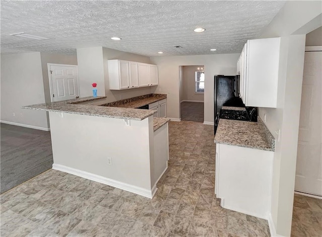 1371 Blazing Star Rd, Lawrenceville, GA 30045 - kitchen featuring white cabinets, light stone countertops, a kitchen breakfast bar, a peninsula, and range with gas cooktop