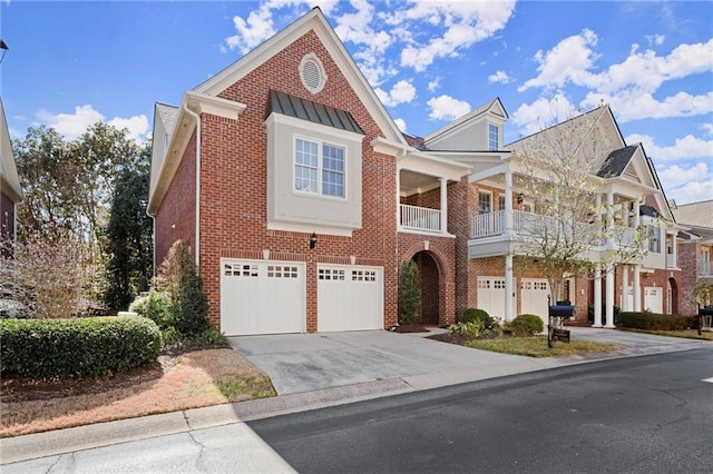 view of front of house featuring driveway, a garage, metal roof, a standing seam roof, and brick siding