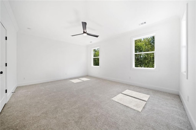 spare room with ceiling fan, light colored carpet, and a wealth of natural light