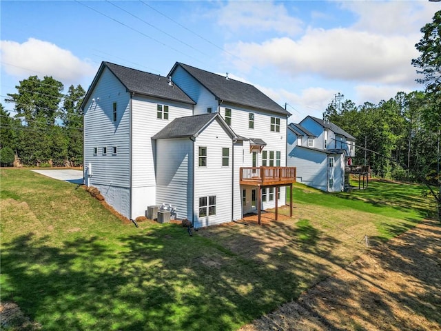 rear view of house with cooling unit, a wooden deck, and a lawn