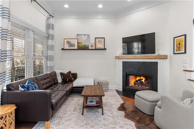 living room with hardwood / wood-style flooring, a tile fireplace, and crown molding