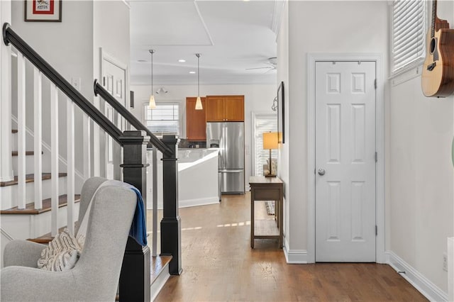 interior space with stainless steel fridge, ceiling fan, hanging light fixtures, hardwood / wood-style floors, and ornamental molding