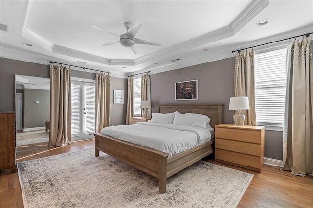 bedroom featuring a raised ceiling, ceiling fan, and light wood-type flooring