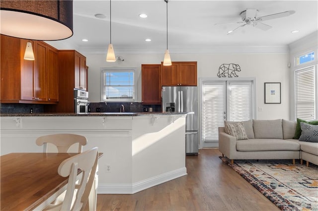 kitchen featuring tasteful backsplash, a breakfast bar area, hanging light fixtures, stainless steel appliances, and light wood-type flooring