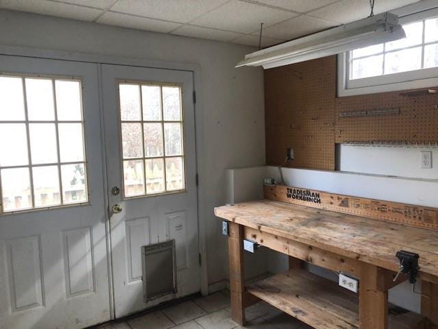 doorway featuring a workshop area, a wealth of natural light, light tile patterned flooring, and a paneled ceiling